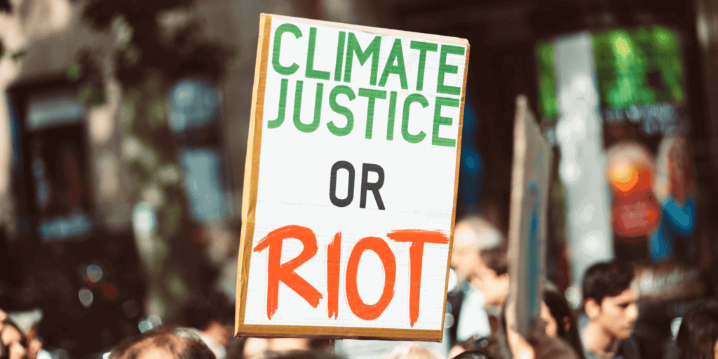 Placa de protesto com mensagem sobre justiça climática e a necessidade de ação urgente.