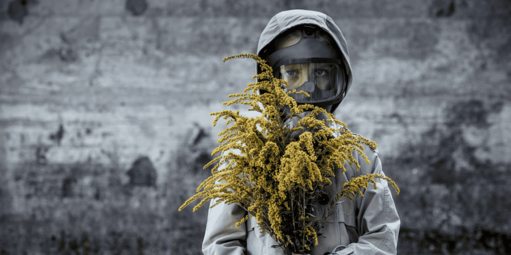 ALT: Médico em área de risco climático com equipamento de proteção e flor de calándula.